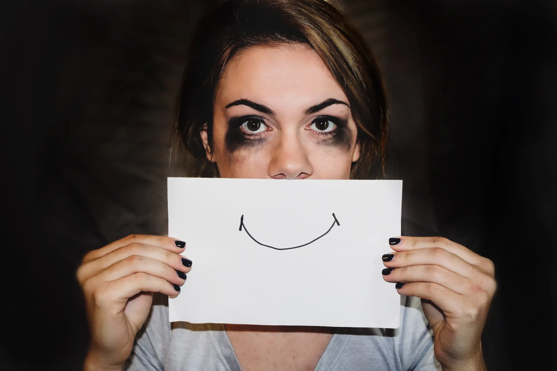 Person holding a white paper with a happy face on it